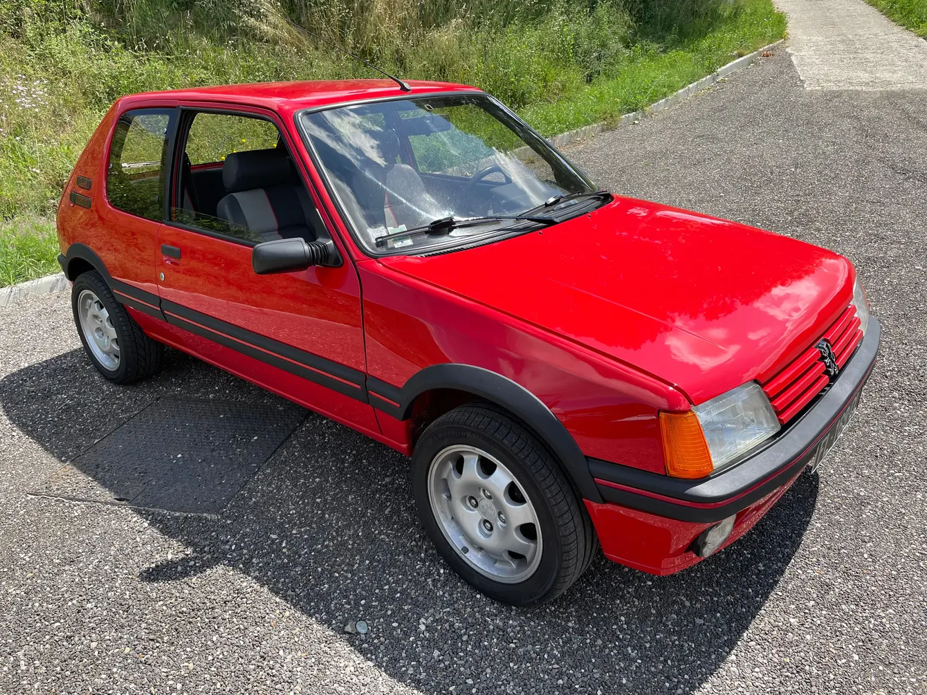 Peugeot 205 rouge vue de trois quarts avant