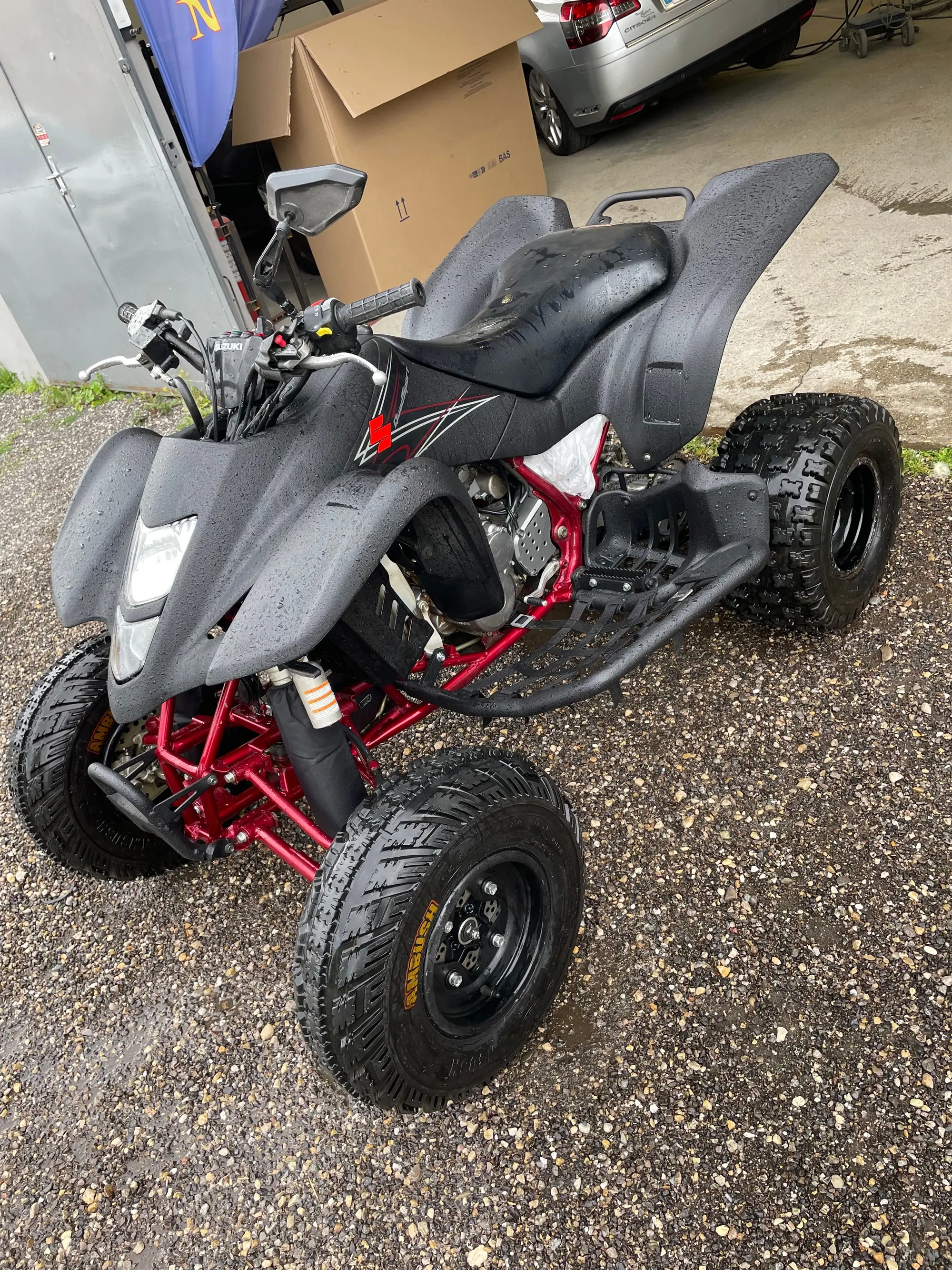 Quad noir à châssis rouge, garé sur le gravier